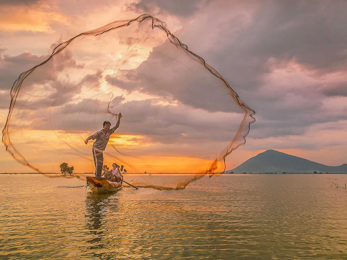 Ngư dân thả lưới trên Hồ Dầu Tiếng lúc hoàng hôn, xa xa là Núi Bà Đen. (Nguồn: Sưu tầm)&nbsp;