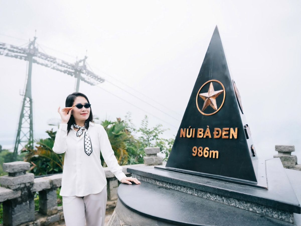 Du khách check-in bên cạnh cột mốc 986 m trên đỉnh núi.