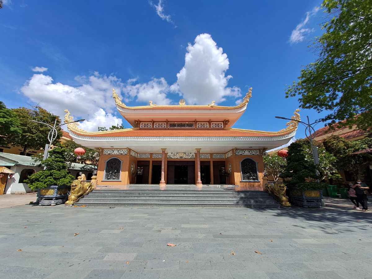 Chùa Hoằng Pháp nổi bật giữa sân rộng dưới trời xanh ngày nắng. 
